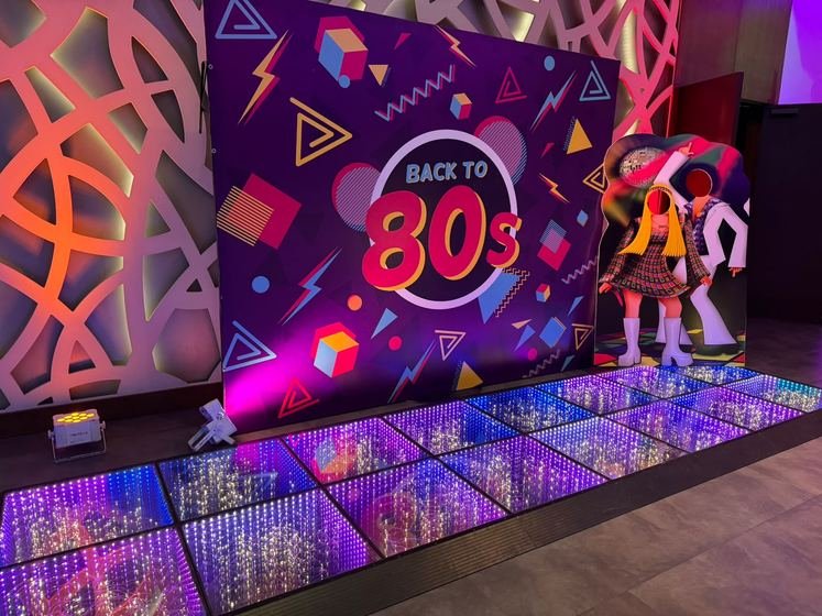 Pista de baile iluminada frente a la mampara «Back to the 80s»