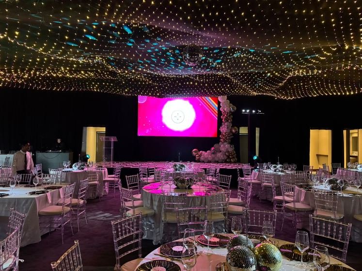 El salón montado para la cena, con mesas redondas y techo de luces