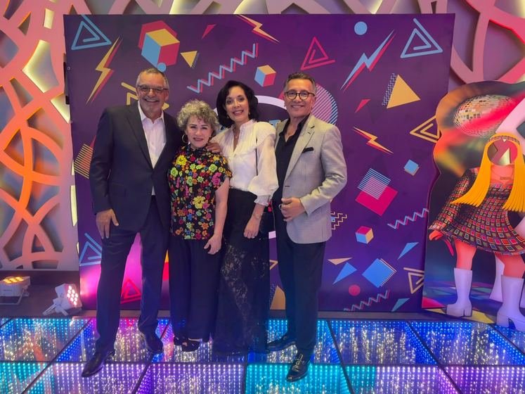 Cuatro invitados posando frente a la mampara «Back to the 80s»